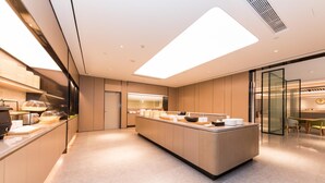 Una cocina moderna con una isla central, electrodomésticos integrados y una lámpara de techo luminosa.