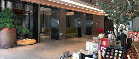 A modern lobby with a reception desk, seating area, and a large potted plant.