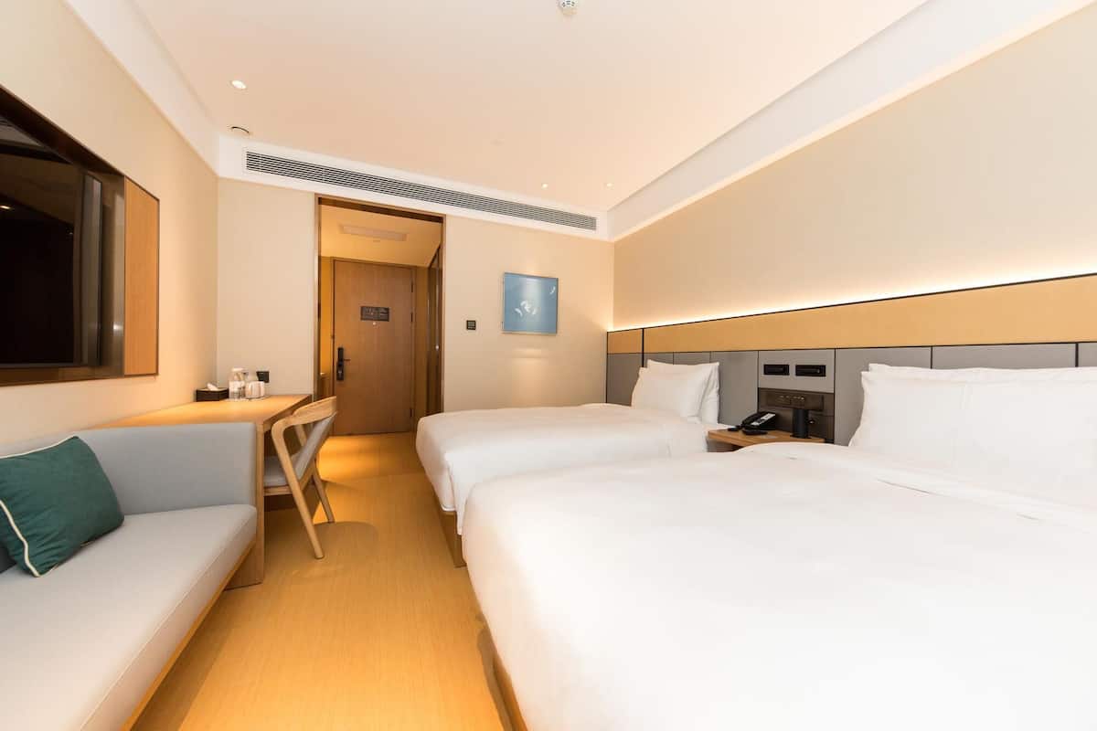 A hotel room with two beds, a desk, a chair, a TV, and a bedside table with a phone.
