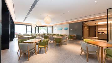 Un restaurante moderno con diversas opciones de asientos, incluyendo mesas y sillas, y un área de cocina a la vista.