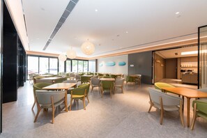 A modern restaurant with a variety of seating options, including tables and chairs, and a visible kitchen area. - Ji Hotel (Tianjin)