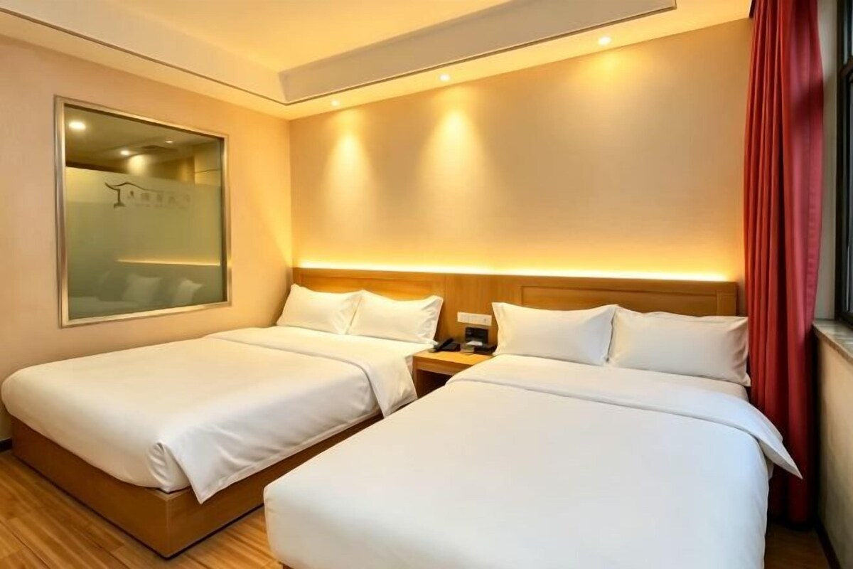 A hotel room with two beds, a nightstand, a mirror, and a window with curtains.