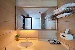 A modern bathroom with a large mirror, a sink, a towel rack, and a toilet paper dispenser. - Very Huating Hotel (Chongqing)