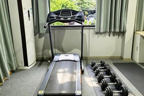 A treadmill with a digital display and a set of dumbbells beside it. - Very Huating Hotel (Chongqing)