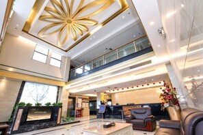 A spacious lobby with a high ceiling, a reception desk, seating area, and a staircase leading to an upper level. - Very Huating Hotel (Chongqing)