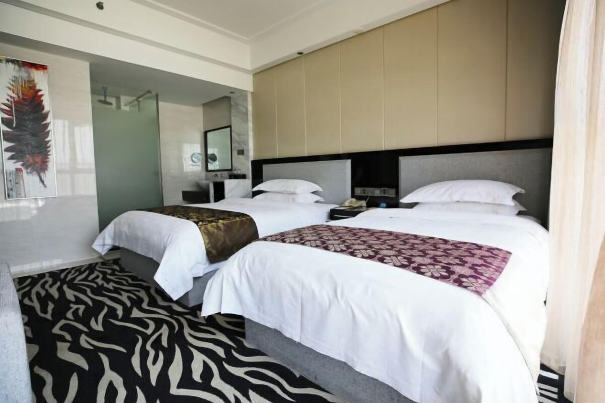 A hotel room with two beds, a zebra-patterned rug, a large mirror, and a feather artwork on the wall.