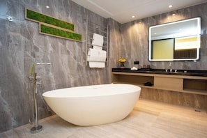 Un baño moderno con una bañera independiente, un perchero, un espejo y un lavabo con mueble.