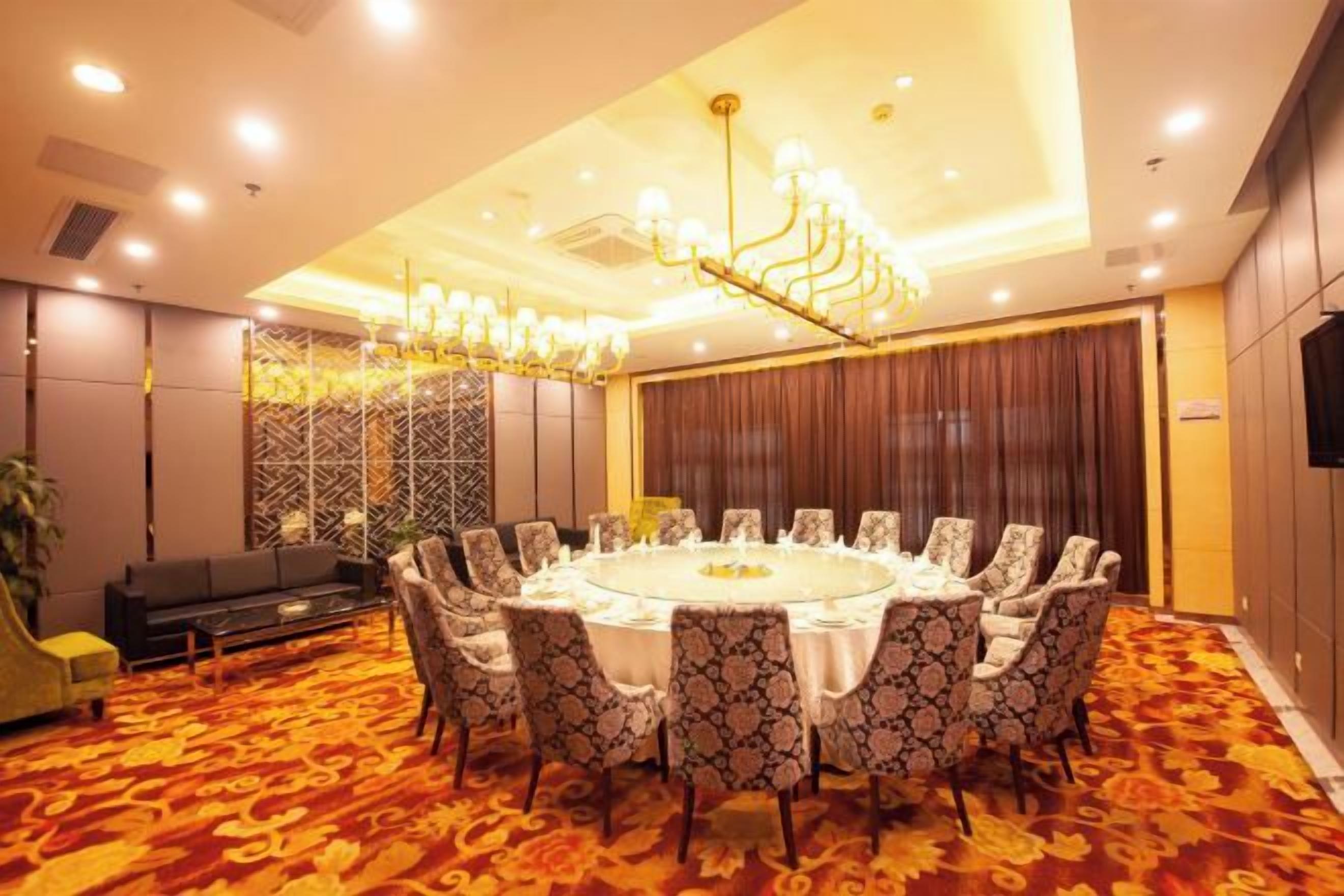 A conference room with a round table, patterned chairs, and a chandelier.
