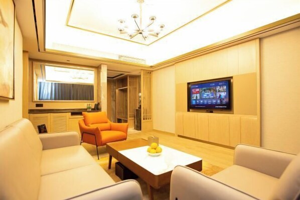 Una sala de estar moderna con un televisor de pantalla plana, un sofá, una mesa de centro con fruta y un candelabro.
