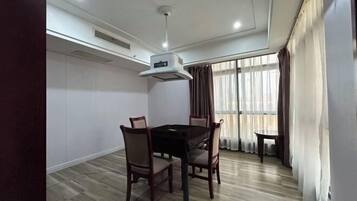 Un coin repas comprenant une table et des chaises, un ventilateur de plafond et une fenêtre avec des rideaux.