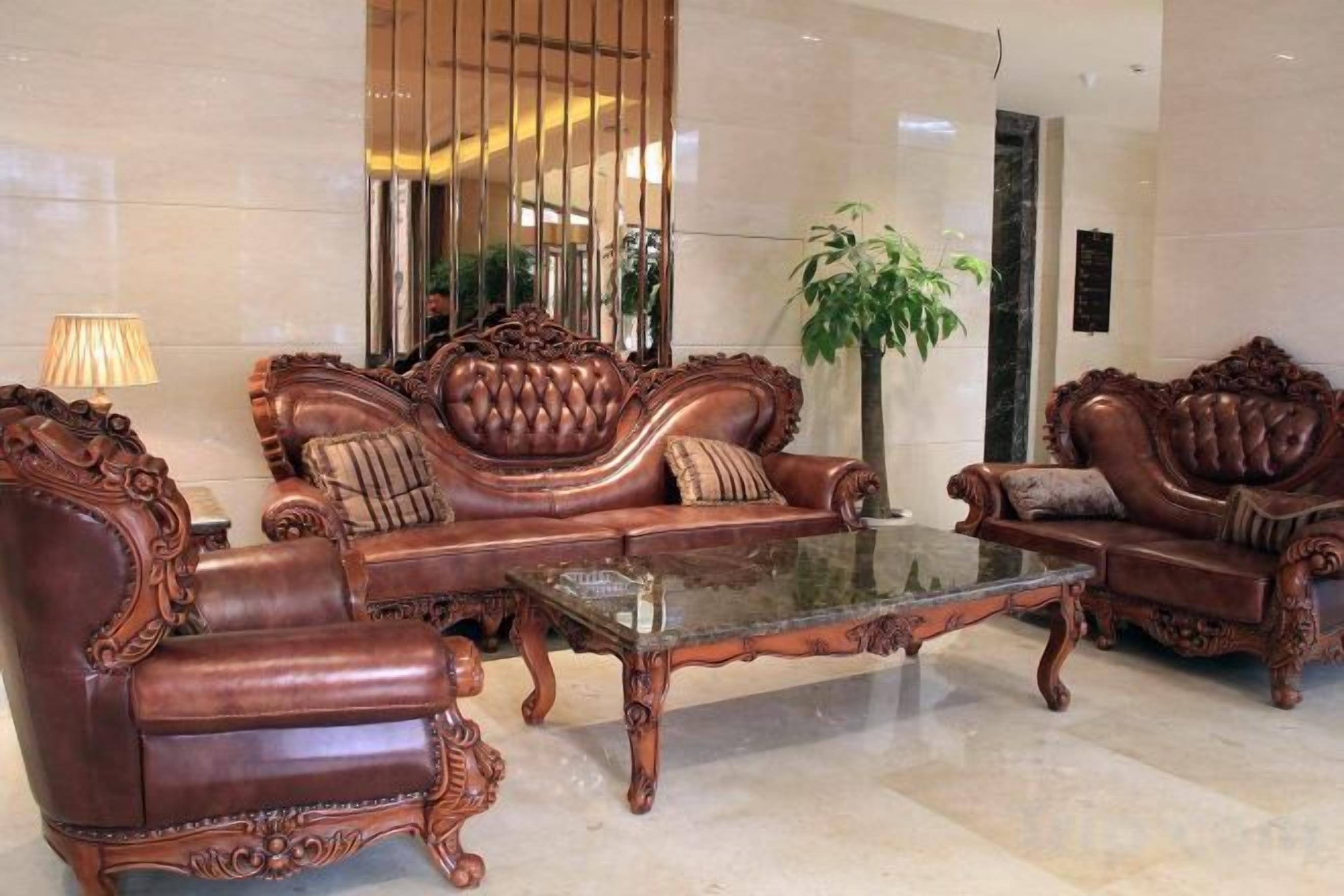 A lobby with a large mirror, a glass coffee table, and two ornate sofas.