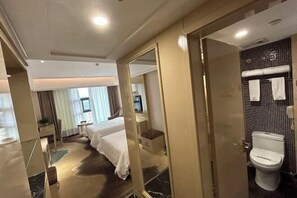 Una habitación de hotel con cama, mesita de noche y baño completo.