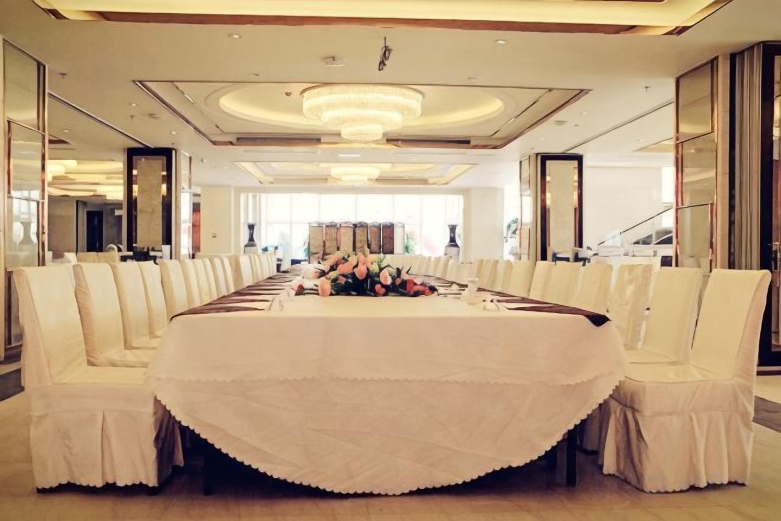 A conference room with a long table, white chairs, and a chandelier.