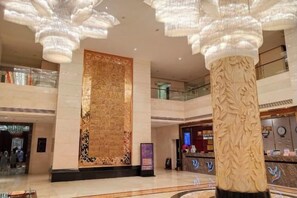 A spacious lobby with a large decorative wall, a reception desk, and a high ceiling with hanging chandeliers. - Xinyuan Hotel Wanzai (Wanzai)