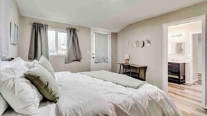 Un dormitorio con una cama, un escritorio y una silla. Hay una ventana con cortinas, una puerta y un espejo en la pared.