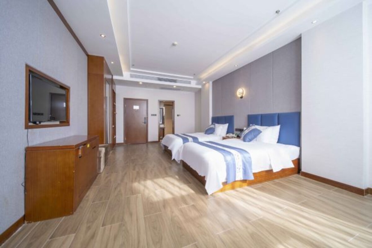 Una habitación de hotel moderna con una cama grande, un escritorio de madera y un espejo.