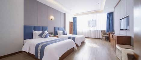 Quarto de hotel com duas camas, uma escrivaninha e uma televisão.