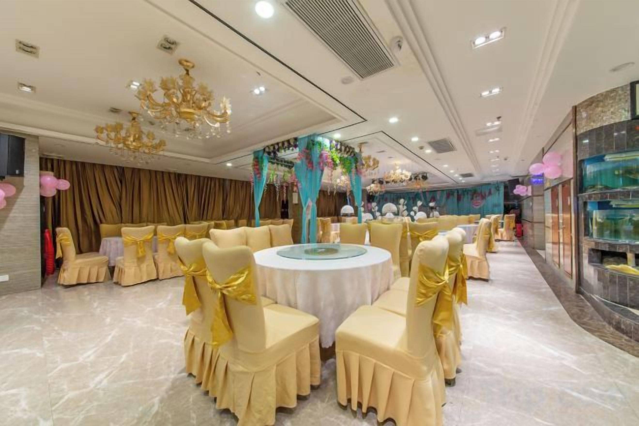 Un salón de banquetes con mesas redondas, sillas y una araña.