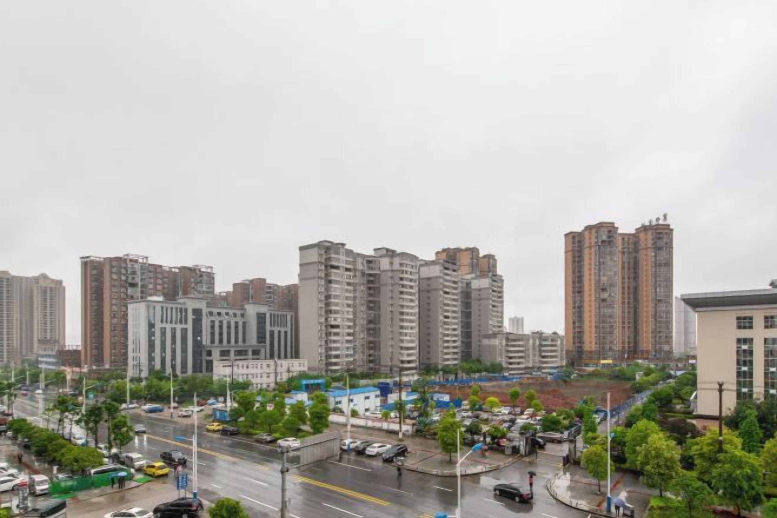 A cityscape with high-rise buildings, a busy street, and a roundabout.