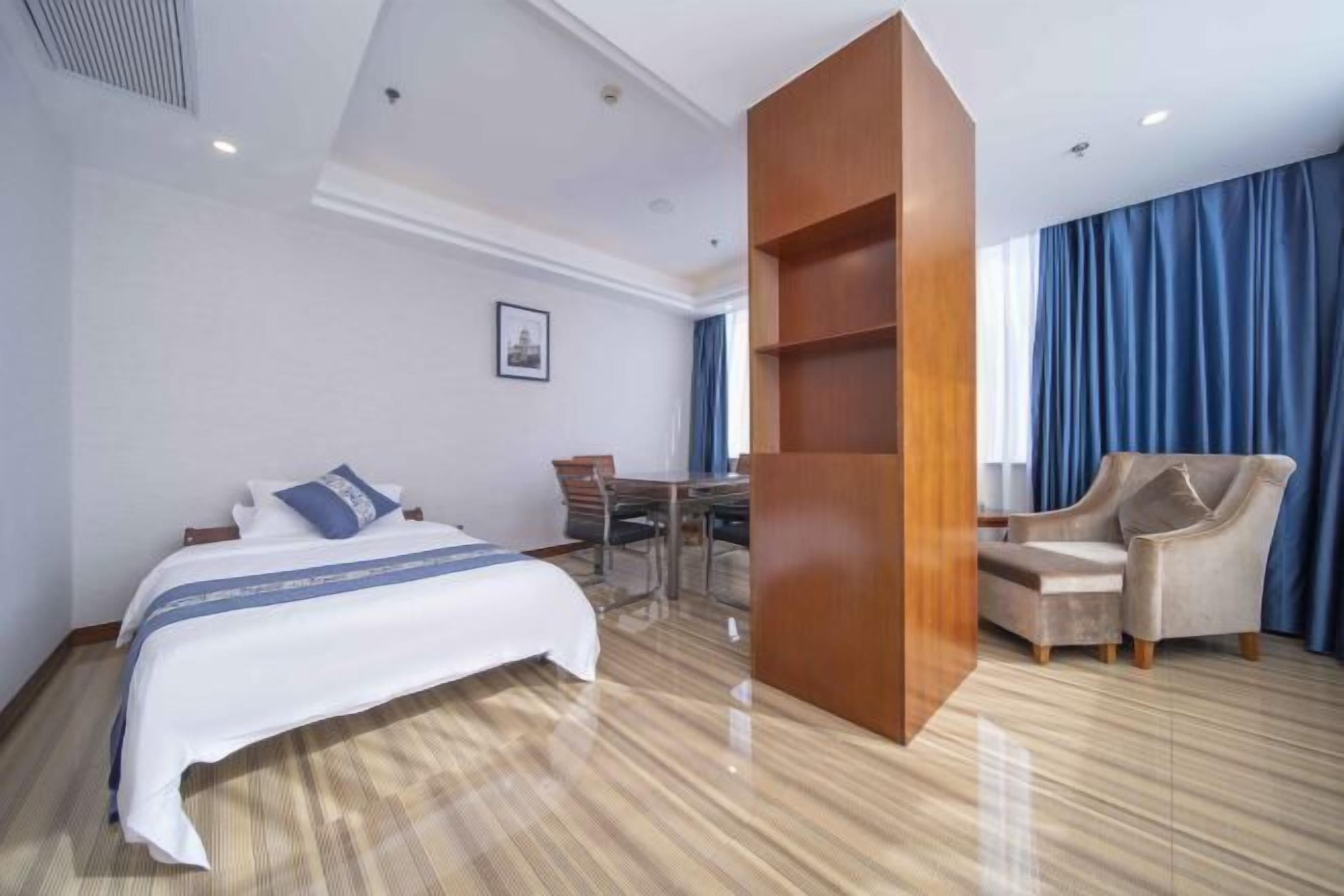 Habitación de hotel con cama, escritorio, silla y una amplia estantería de madera.