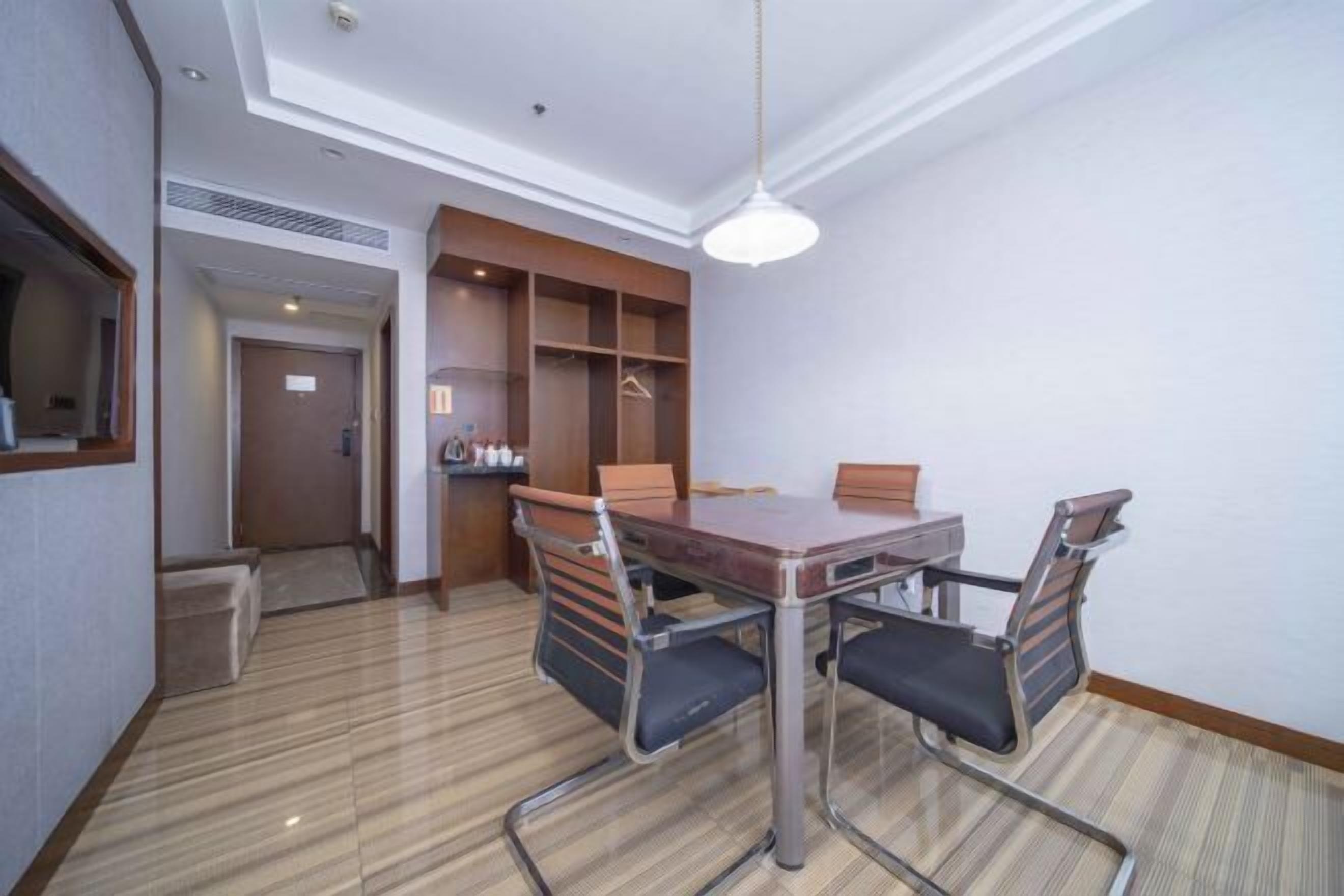 A conference room with a wooden table, four chairs, and a white pendant light.