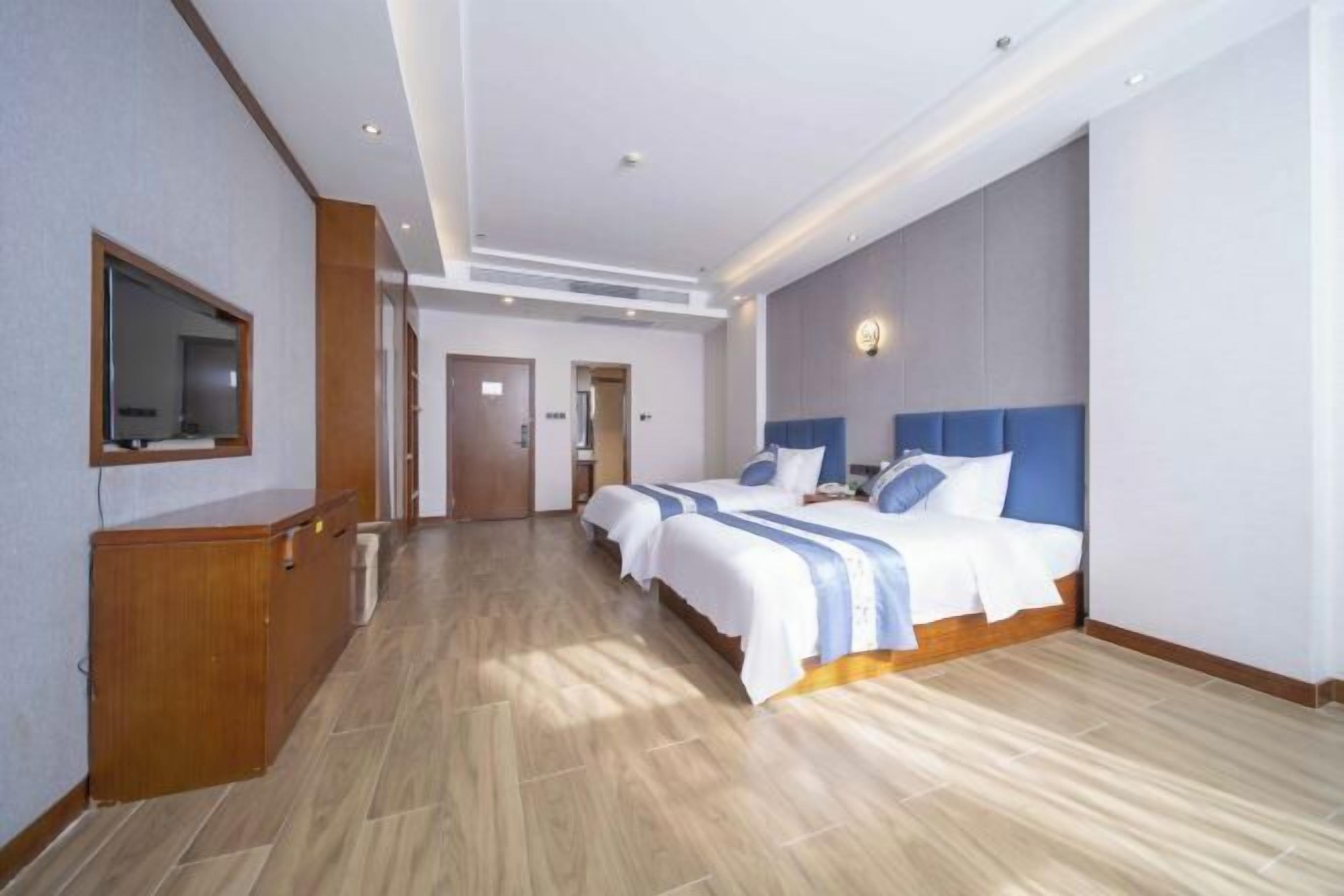 Quarto de hotel moderno com uma cama grande, uma escrivaninha de madeira e um espelho.