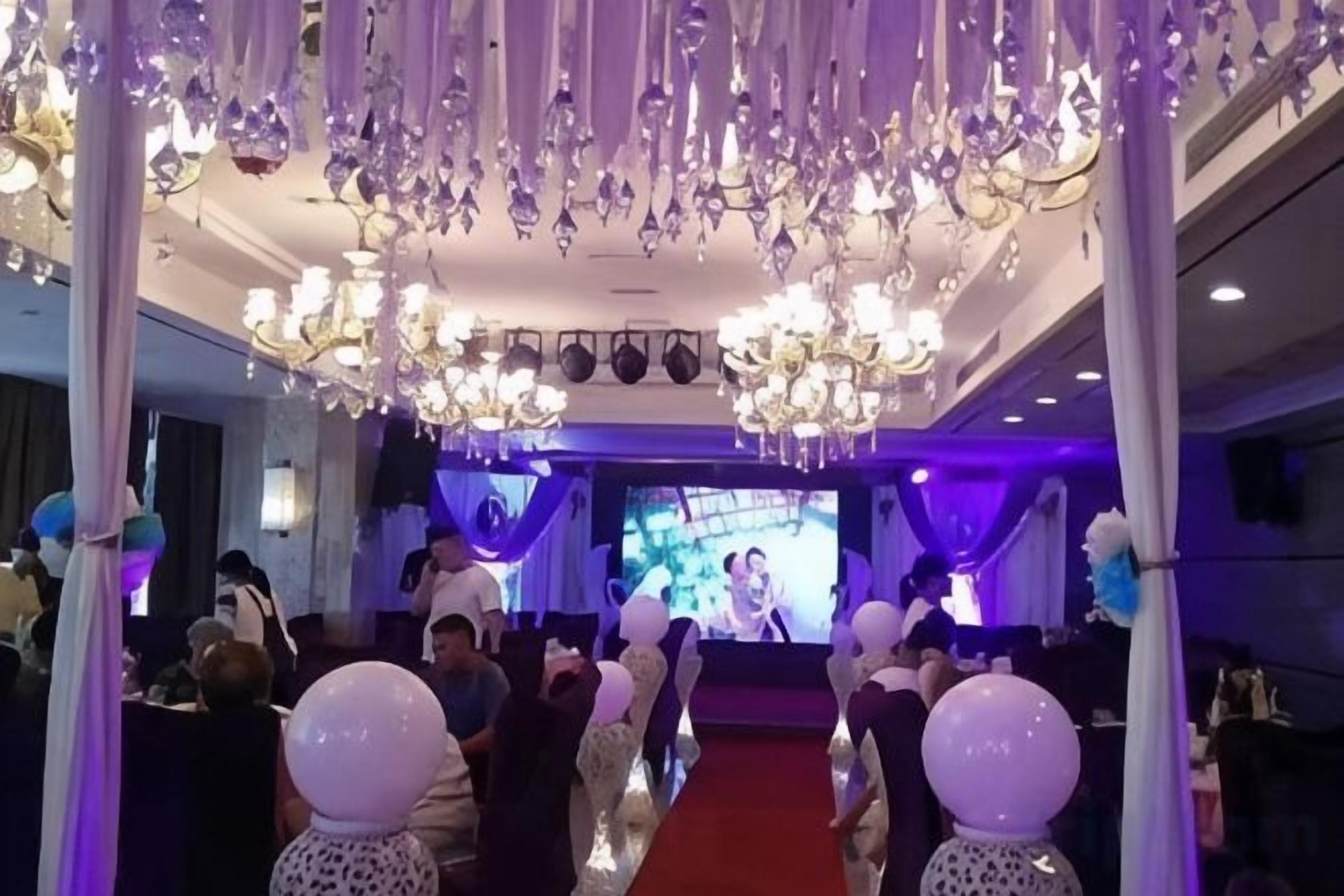 Un evento en interior con escenario, asientos para el público y candelabros.