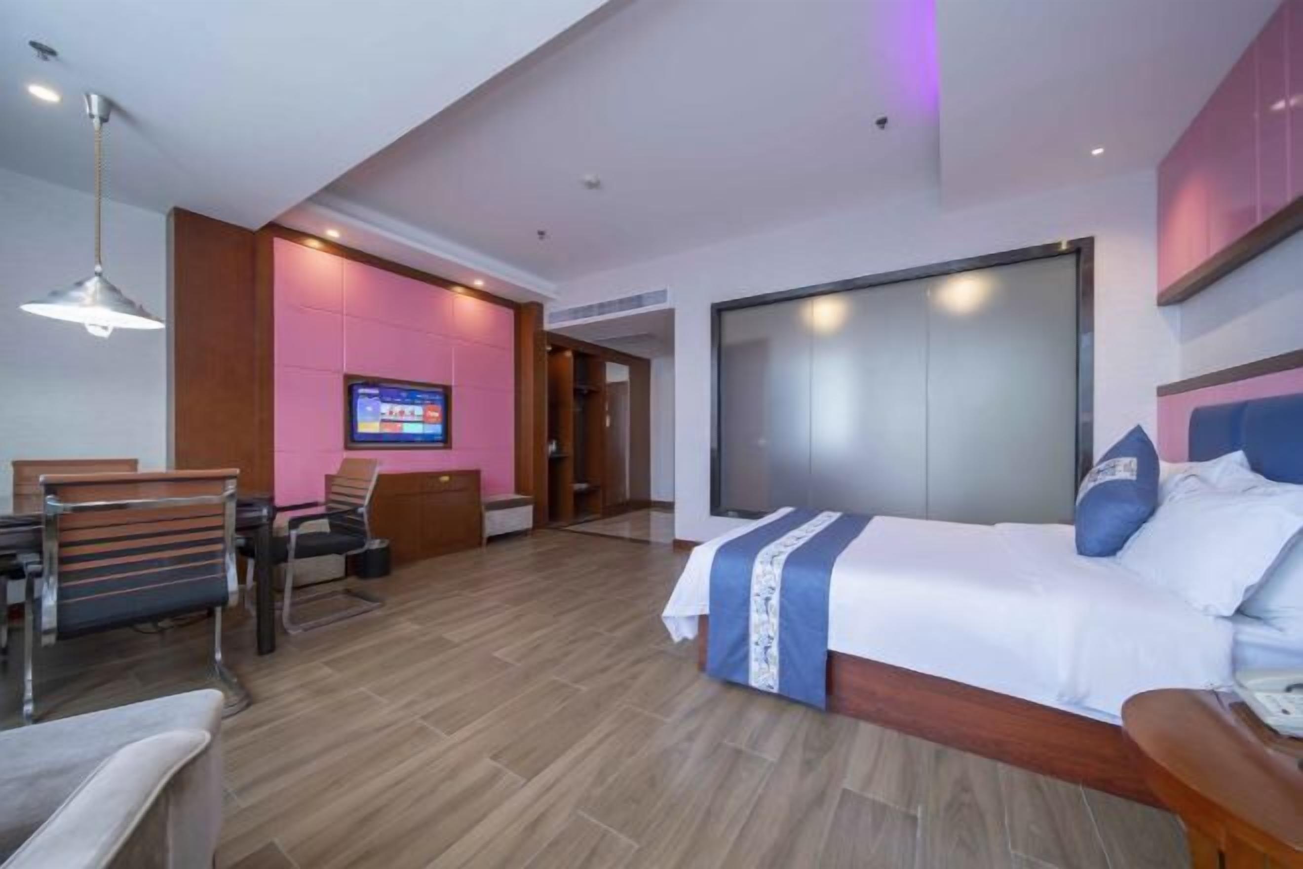 A hotel room with a bed, a TV, a desk, and a chair.