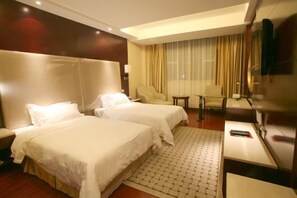 A hotel room with two beds, a desk, a chair, and a TV.