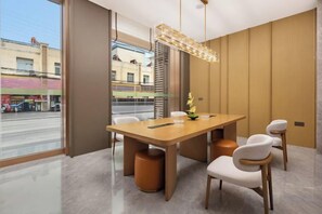 A modern dining area with a wooden table and chairs, a pendant light, and a view of the street outside. - kairuihotel (Jianli)