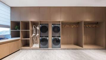 Ein moderner Waschraum mit eingelassenen Waschmaschinen und Trocknern, Holzschränken und einem minimalistischen Design.