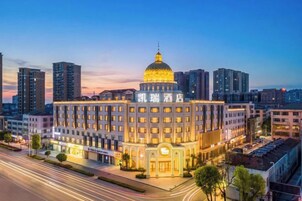 Un hotel con una cúpula destacada y varios pisos, rodeado de edificios modernos.
