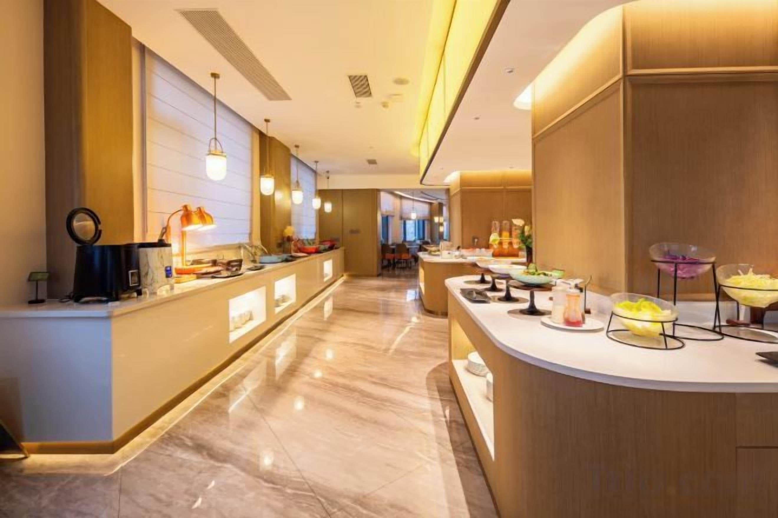 A hotel reception area with a marble floor, a reception desk, and a buffet with various food items.