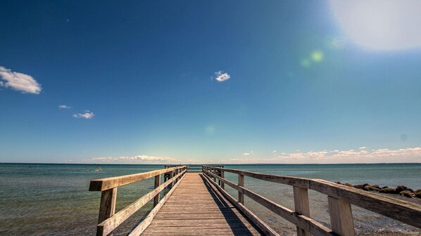 A wooden pier extending into a calm sea under a clear sky.