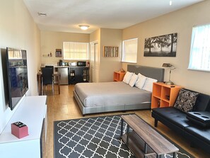 A compact hotel room with a bed, a sofa, a desk, a kitchenette, and a TV. - Private King Suite with W/D near LEGOLAND & Winter Haven Hospital (Winter Haven)