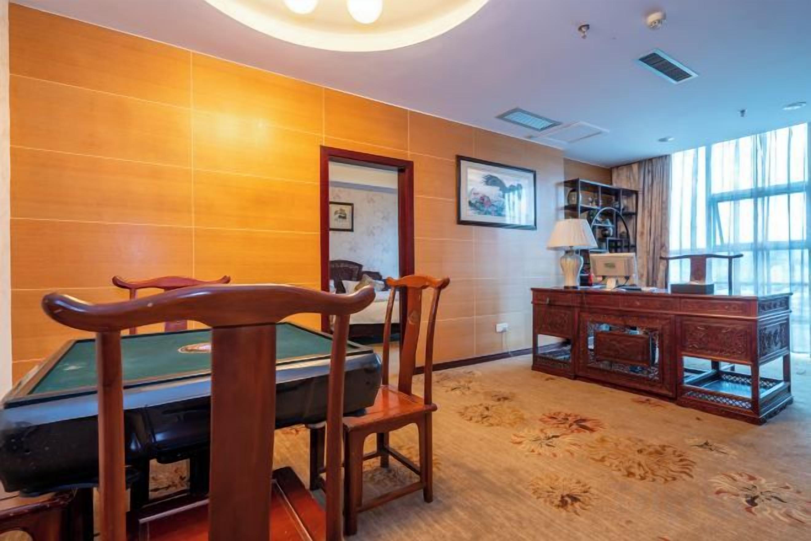 Een kamer met een pooltafel, stoelen, een bureau en een raam.