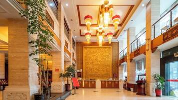 A spacious lobby with a reception desk, potted plants, and a decorative wall.