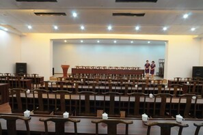 A conference room with rows of chairs, a stage with a podium, and a large screen. - Y. H. Continental Grand Hotel (Jiangle)