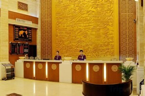 A hotel reception area with a large, intricately carved wall, a reception desk, and a digital display board. - Y. H. Continental Grand Hotel (Jiangle)