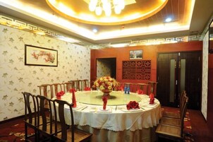Un comedor con una mesa redonda, sillas y un centro de mesa floral.