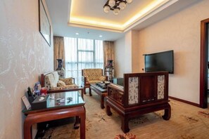 A living room with a sofa, armchairs, a coffee table, and a television mounted on the wall. - Y. H. Continental Grand Hotel (Jiangle)