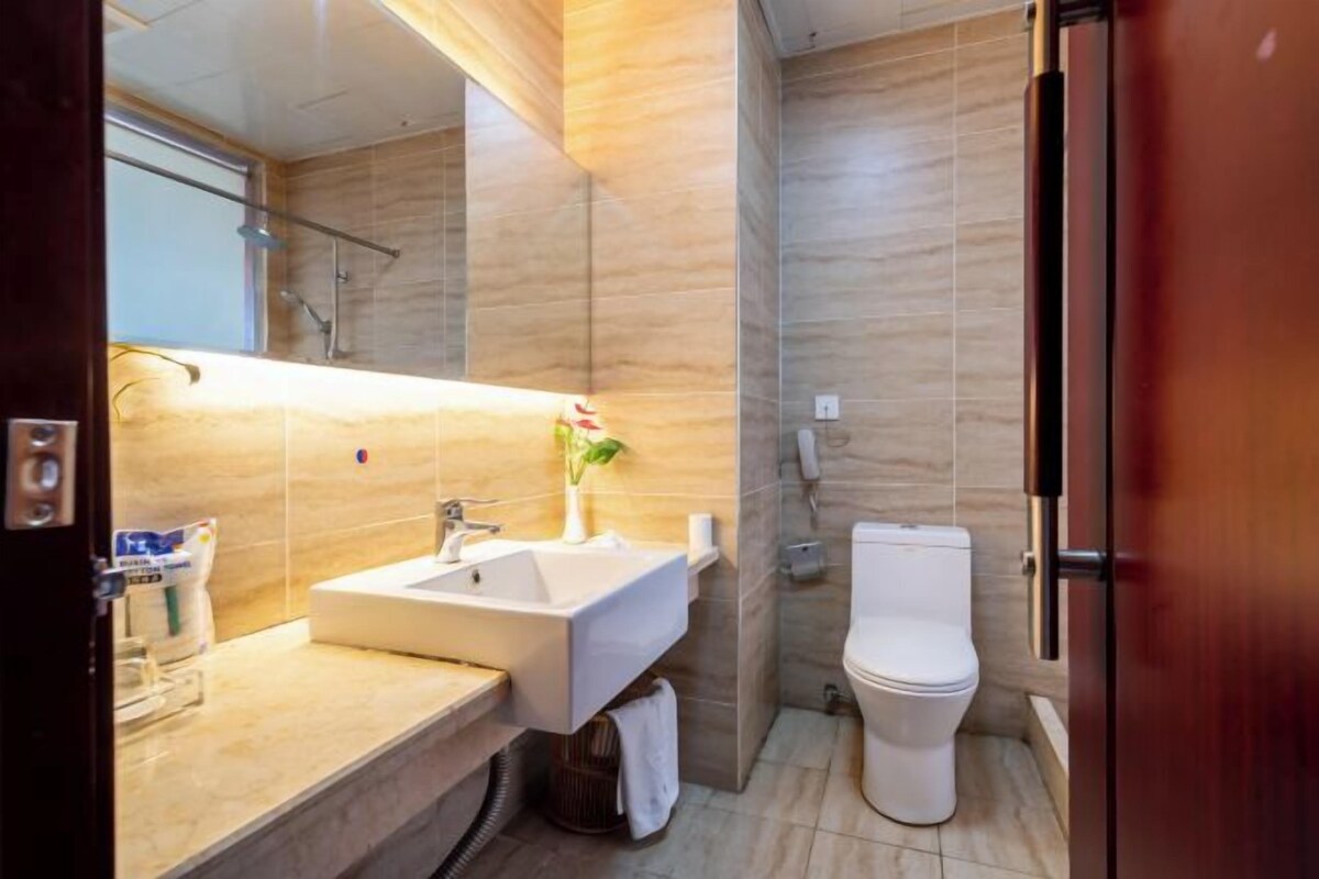 A modern bathroom with a sink, mirror, toilet, and shower.