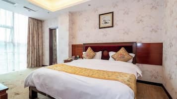 A hotel room with a large bed, a wooden headboard, a nightstand, and a window with curtains.