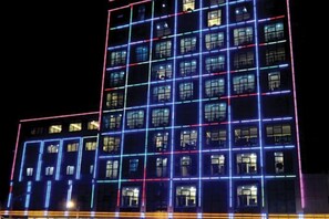 A multi-story building with illuminated window outlines and a grid-like facade. - Y. H. Continental Grand Hotel (Jiangle)