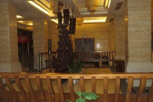 Un vestíbulo con mostrador de recepción, una escalera y una escultura metálica decorativa.