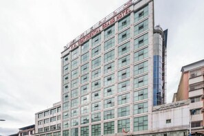 A multi-story hotel building with a modern facade, large windows, and a prominent signage at the top.