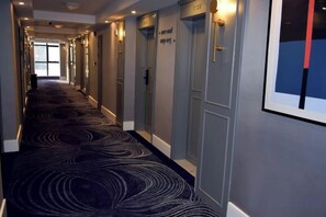A hotel corridor with a patterned carpet, doors with room numbers, and a framed picture on the wall. - Yicheng Hotel (Dafang)