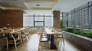 Un comedor moderno con mesas y sillas de madera, ventanas amplias y vistas a zonas verdes.