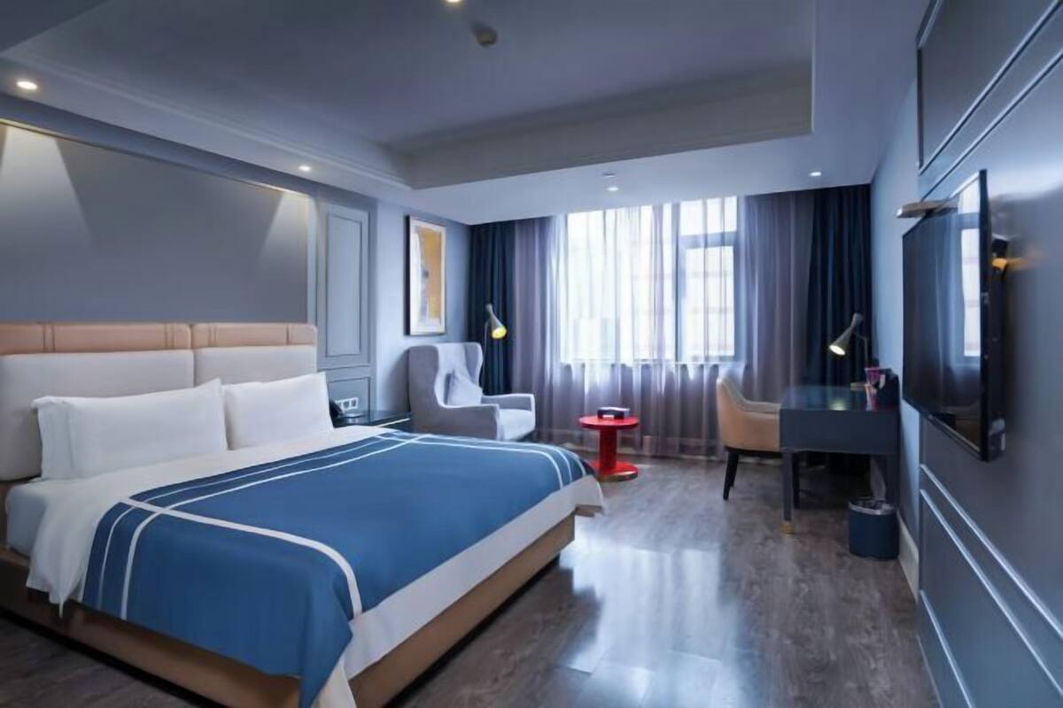 Una habitación de hotel moderna con una cama grande, un escritorio, una silla y un televisor.