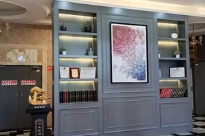 A wall with shelves displaying various items, a framed artwork, and a decorative statue. - Yicheng Hotel (Dafang)